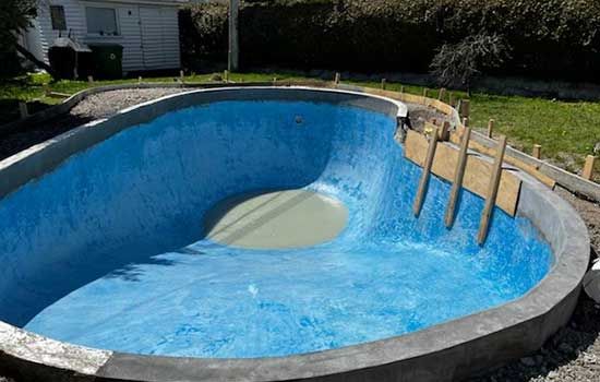 Une piscine bleue est en cours de construction dans une cour.