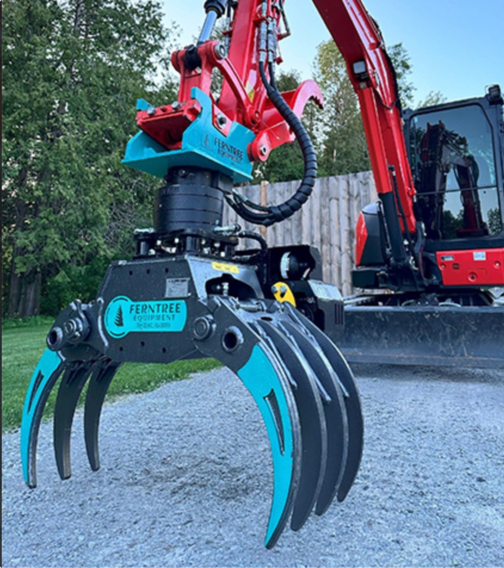 Red and teal excavator with grapple attachment, outdoors.