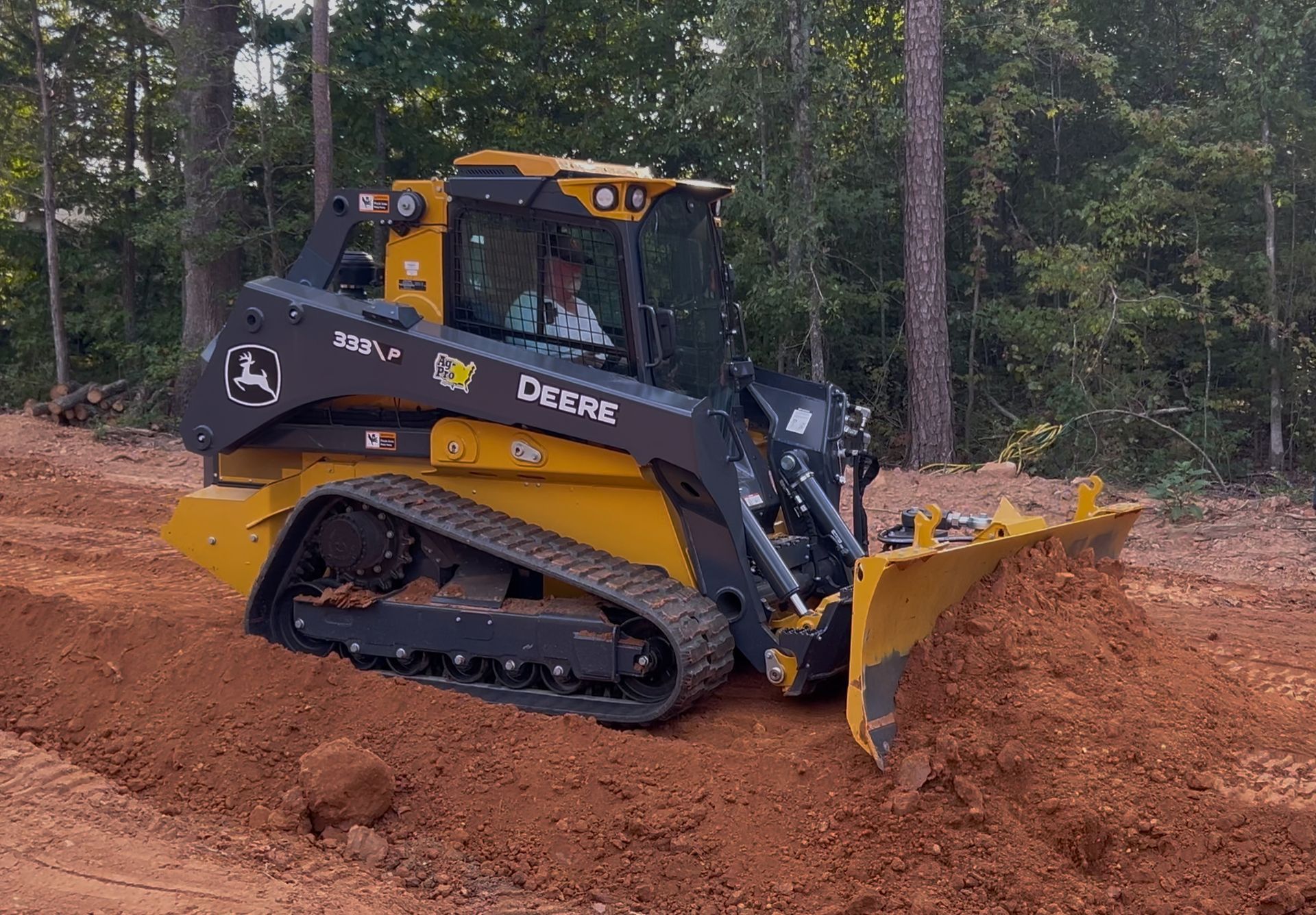 Yellow skid steer loader on a construction site, with a black cab and tracks.