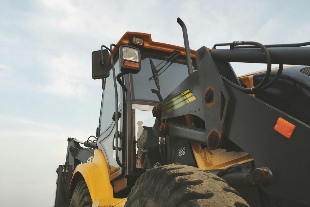 Yellow and black construction vehicle against a cloudy sky.