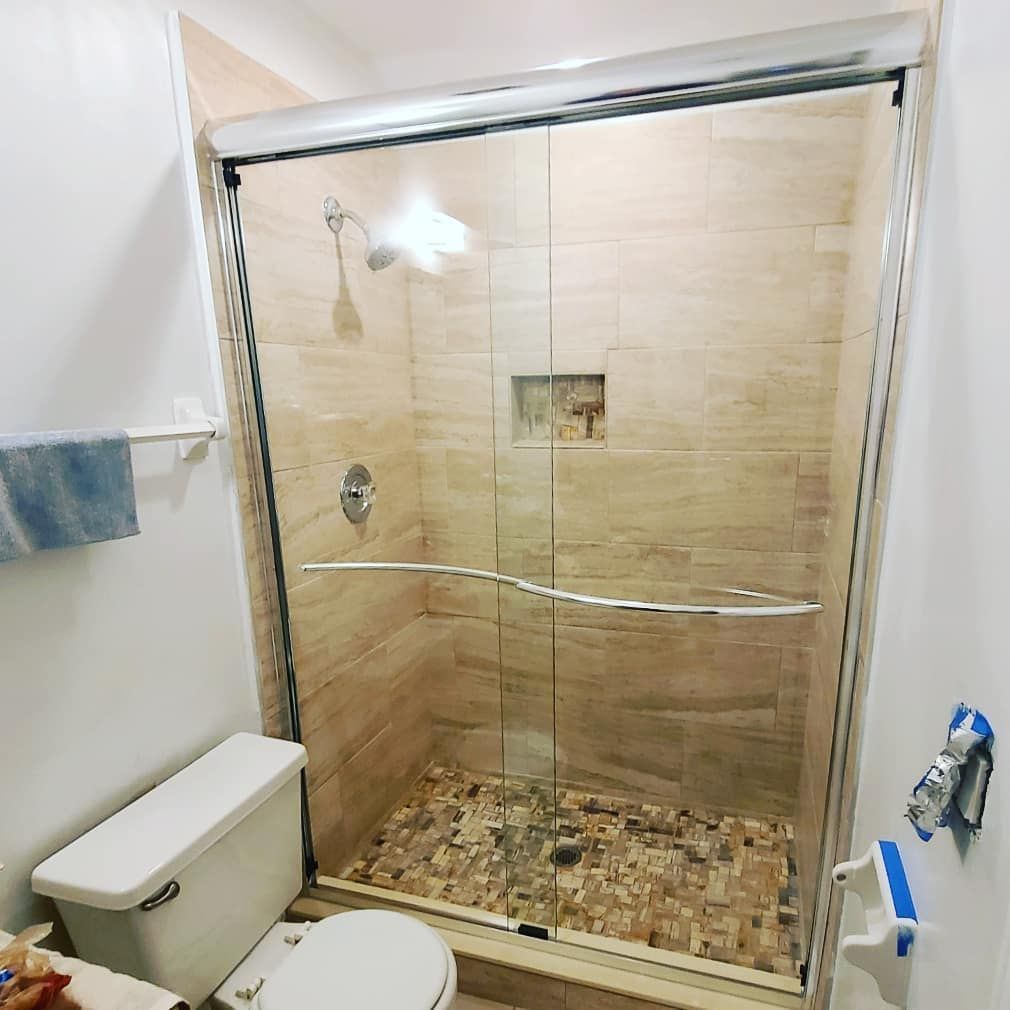 A bathroom with a toilet and a shower with a sliding glass door.