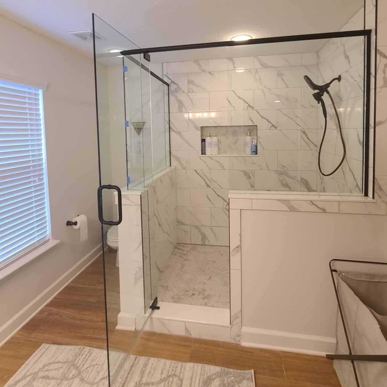 A bathroom with a walk in shower and a window.