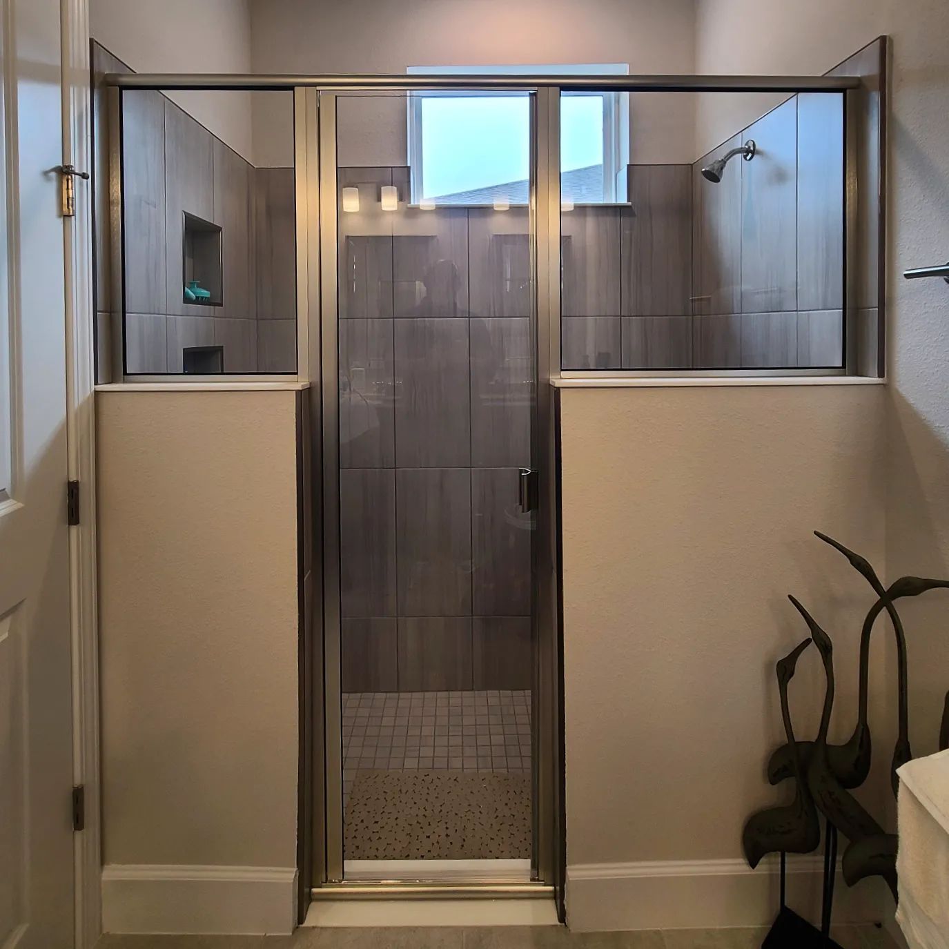 A bathroom with a walk in shower and a window.