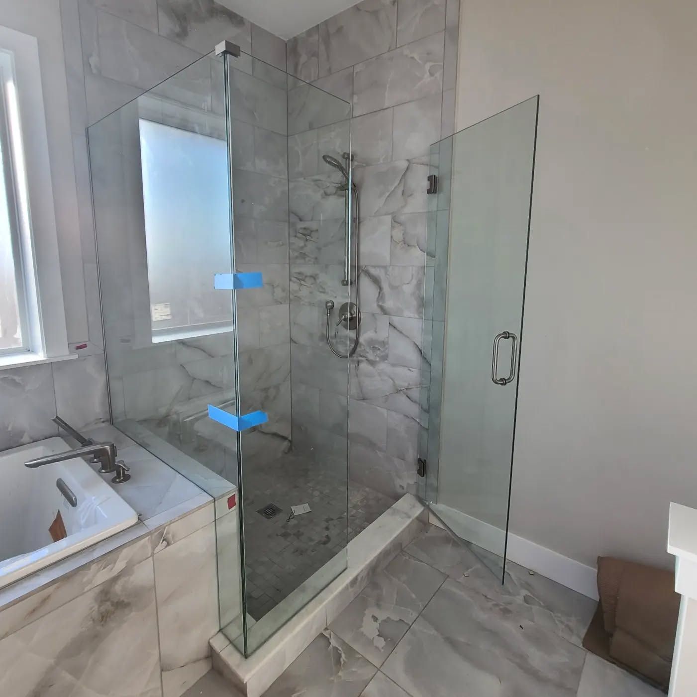 A bathroom with a walk in shower and a tub.