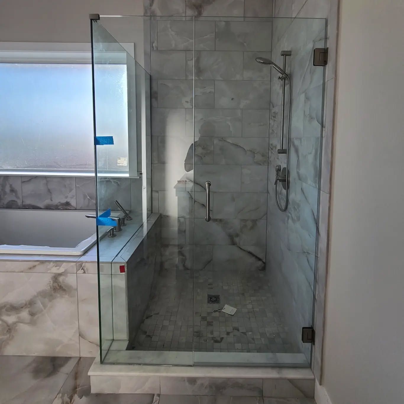 A bathroom with a glass shower door and a bathtub.