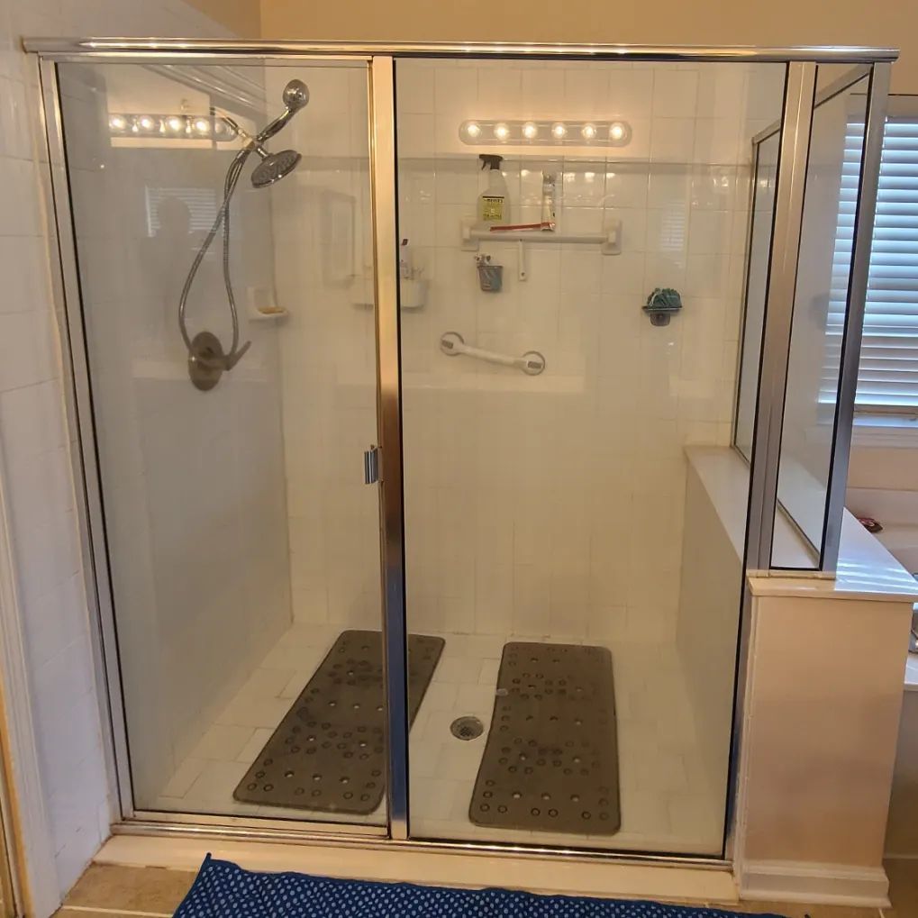 A bathroom with a walk in shower with a sliding glass door