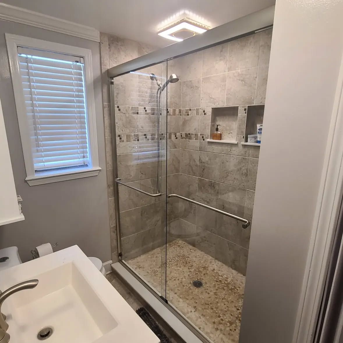 A bathroom with a sliding glass shower door and a sink.