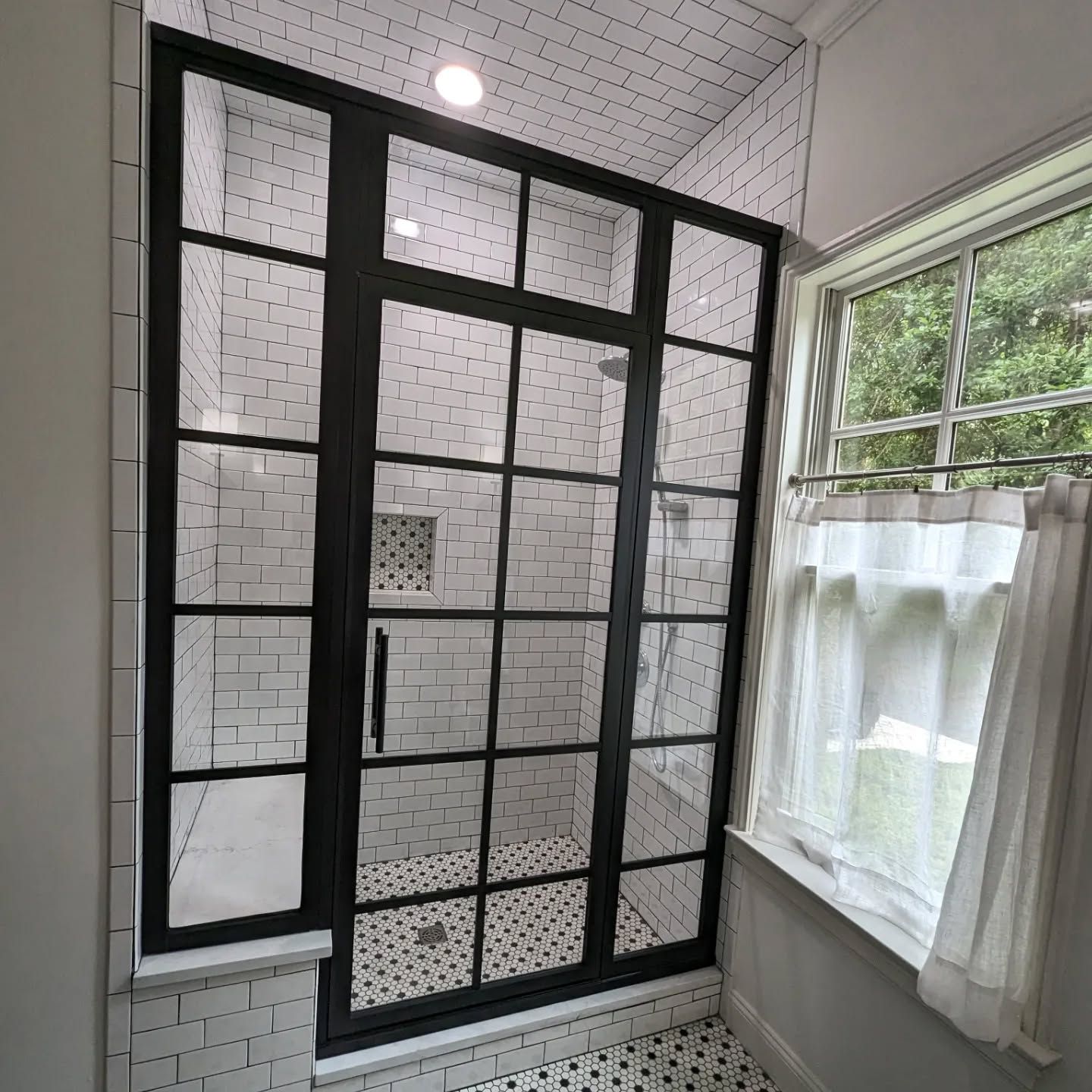 A bathroom with a walk in shower and a window.