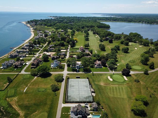 An aerial view of a residential area with a tennis court and a golf course.