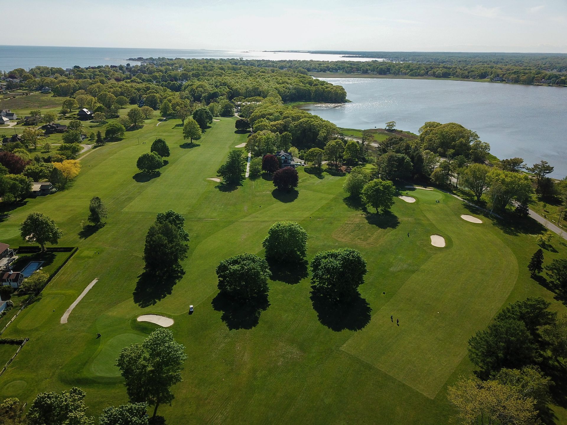 An aerial view of a golf course with a lake in the background