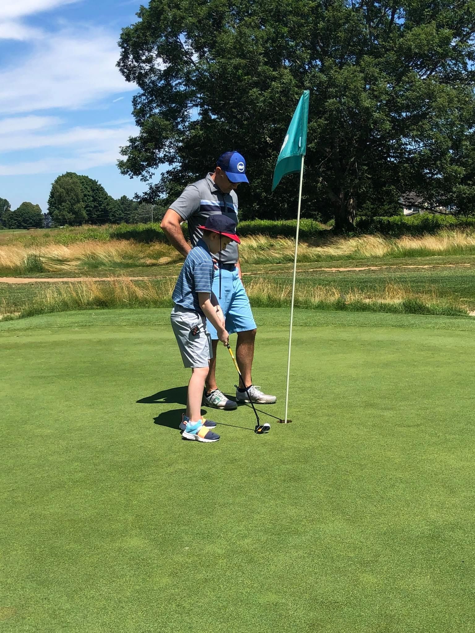 A man and a boy are playing golf on a green.