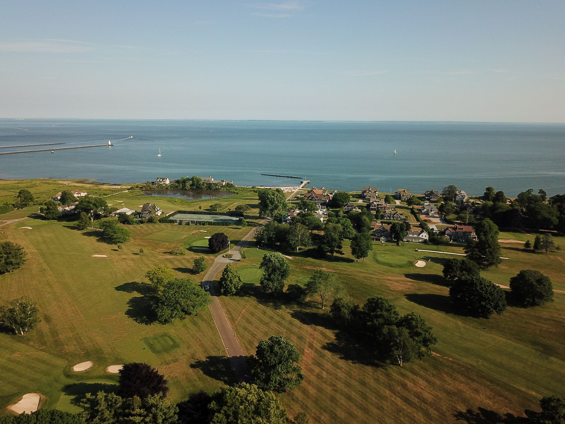 An aerial view of a golf course with a body of water in the background.