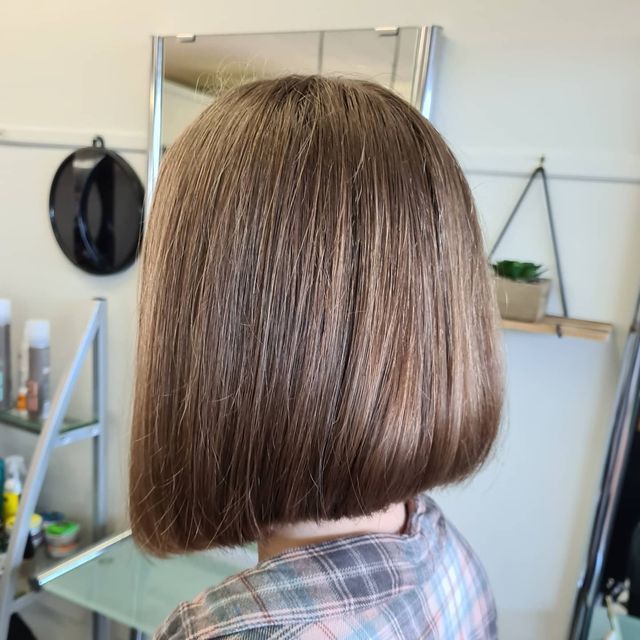 A Woman With Short Brown Hair is Standing in Front of a Mirror — Lush Hair Studio in Tumbi Umbi, NSW