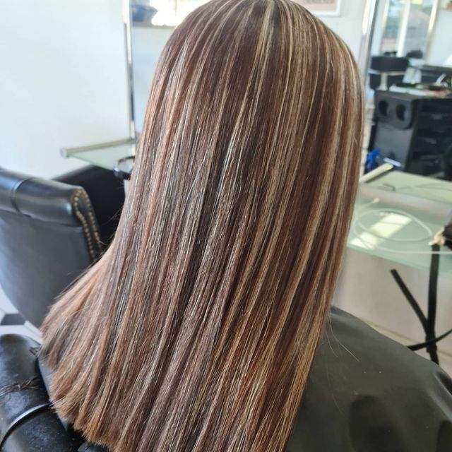 A Woman With Long Brown Hair is Sitting in a Chair — Lush Hair Studio in Tumbi Umbi, NSW