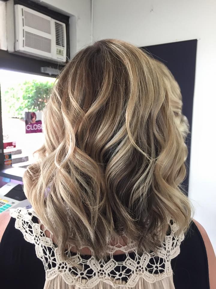 A Woman With Blonde Hair is Standing in Front of a Window in a Salon — Lush Hair Studio in Tumbi Umbi, NSW