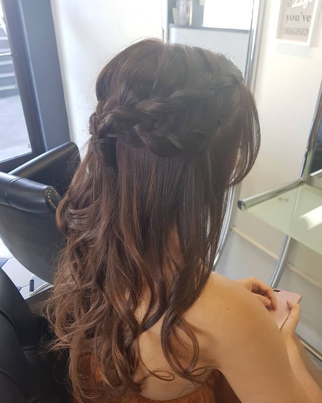 A Woman is Sitting in a Chair With Her Hair in a Half Up Half Down Braid — Lush Hair Studio in Tumbi Umbi, NSW