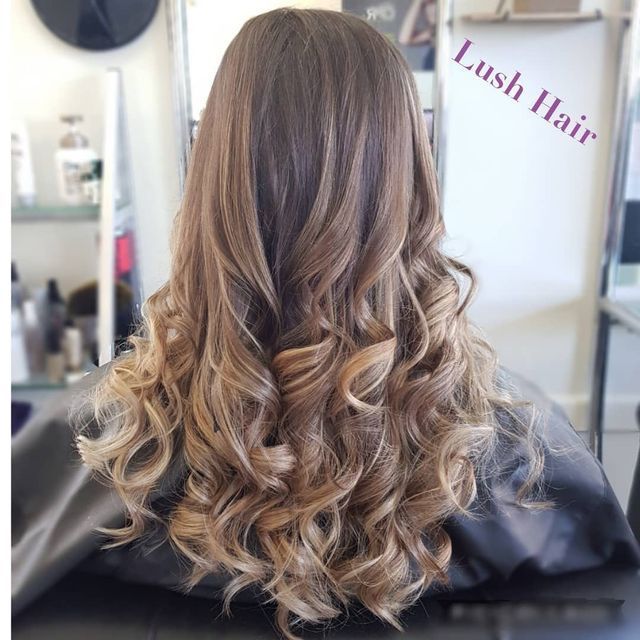 A Woman With Long Curly Hair is Sitting in a Chair in a Salon — Lush Hair Studio in Tumbi Umbi, NSW