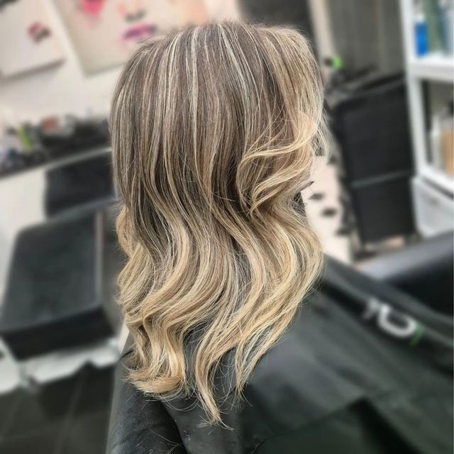 A Woman With Long Blonde Hair is Sitting in a Chair in a Salon — Lush Hair Studio in Tumbi Umbi, NSW