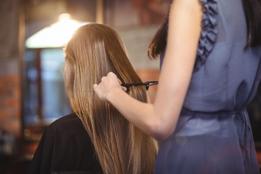 A Woman is Getting Her Hair Cut by a Hairdresser in a Salon — Lush Hair Studio in Tumbi Umbi, NSW