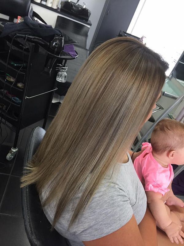 A Woman is Sitting in a Chair Holding a Baby — Lush Hair Studio in Tumbi Umbi, NSW