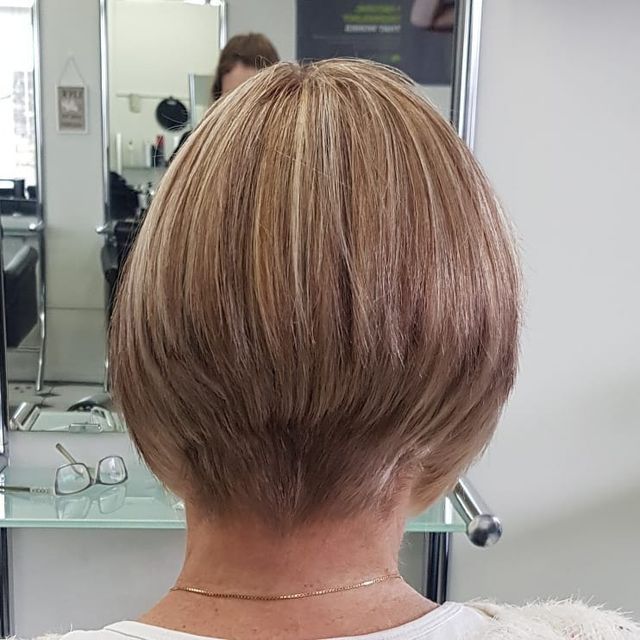 A Woman With Short Blonde Hair is Sitting in Front of a Mirror in a Salon — Lush Hair Studio in Tumbi Umbi, NSW