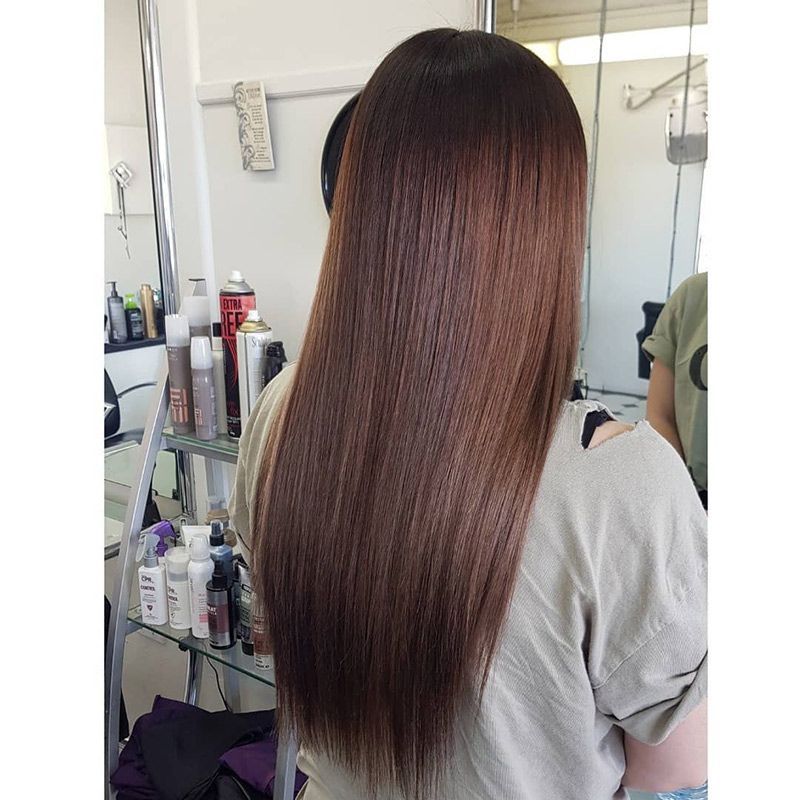 A Woman With Long Brown Hair is Standing in Front of a Mirror in a Salon — Lush Hair Studio in Tumbi Umbi, NSW