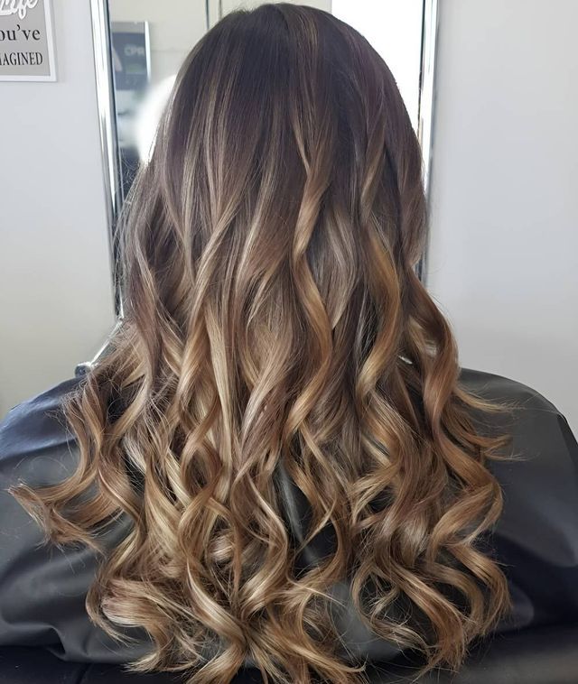 A Woman With Long Curly Hair is Sitting in Front of a Mirror — Lush Hair Studio in Tumbi Umbi, NSW