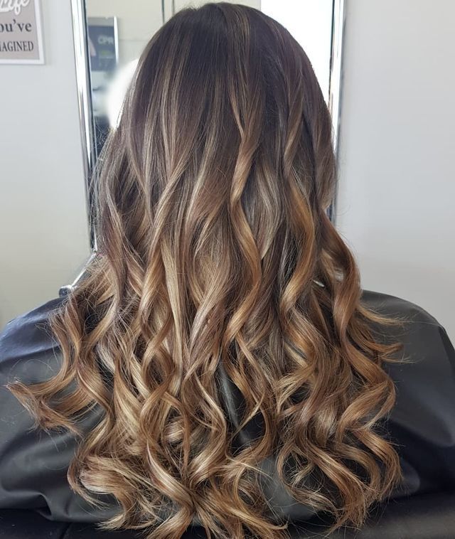 A Woman With Long Curly Hair is Sitting in Front of a Mirror — Lush Hair Studio in Tumbi Umbi, NSW