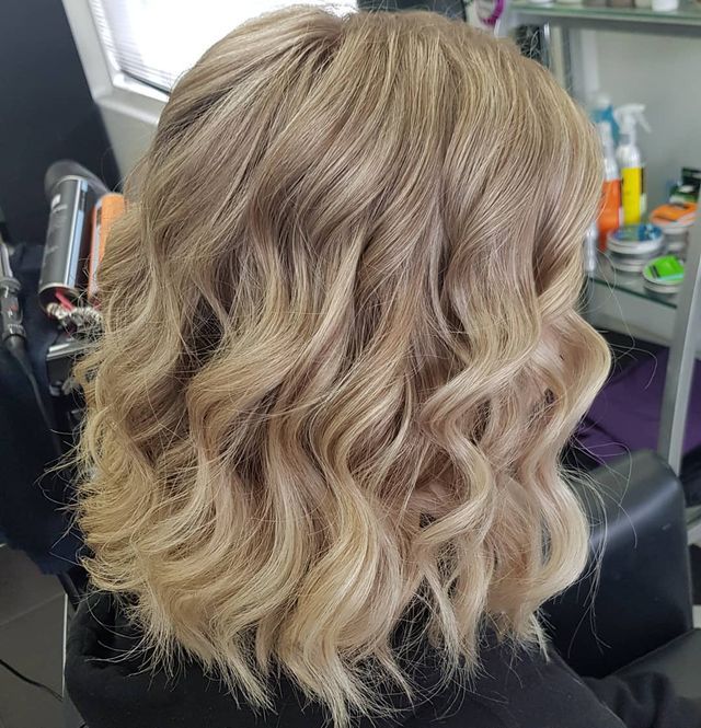 A Woman With Blonde Wavy Hair is Sitting in a Chair in a Salon — Lush Hair Studio in Tumbi Umbi, NSW