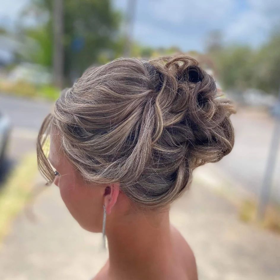 A Woman is Wearing Her Hair in a Messy Bun — Lush Hair Studio in Tumbi Umbi, NSW