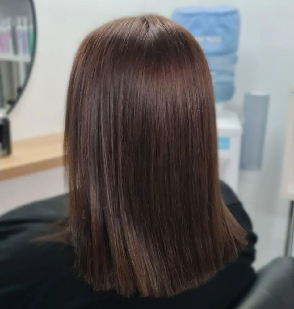 A Woman With Long Brown Hair is Sitting in a Chair in a Salon — Lush Hair Studio in Tumbi Umbi, NSW