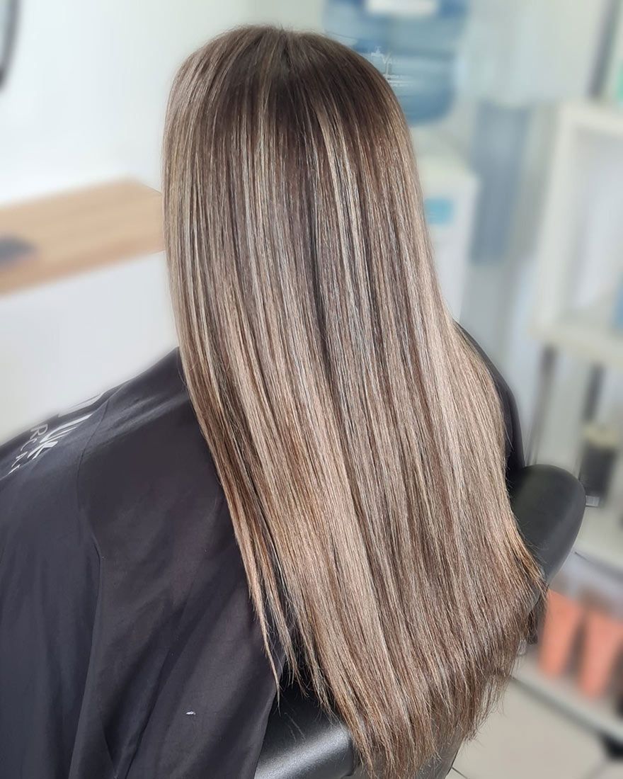 A Woman With Long Brown Hair is Sitting in a Chair in a Salon — Lush Hair Studio in Tumbi Umbi, NSW