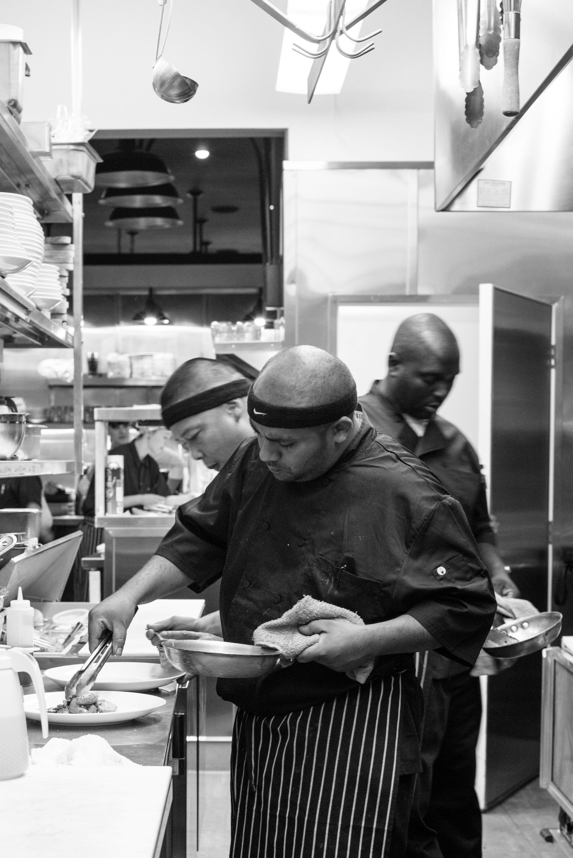 A group of men are standing in a kitchen preparing food.