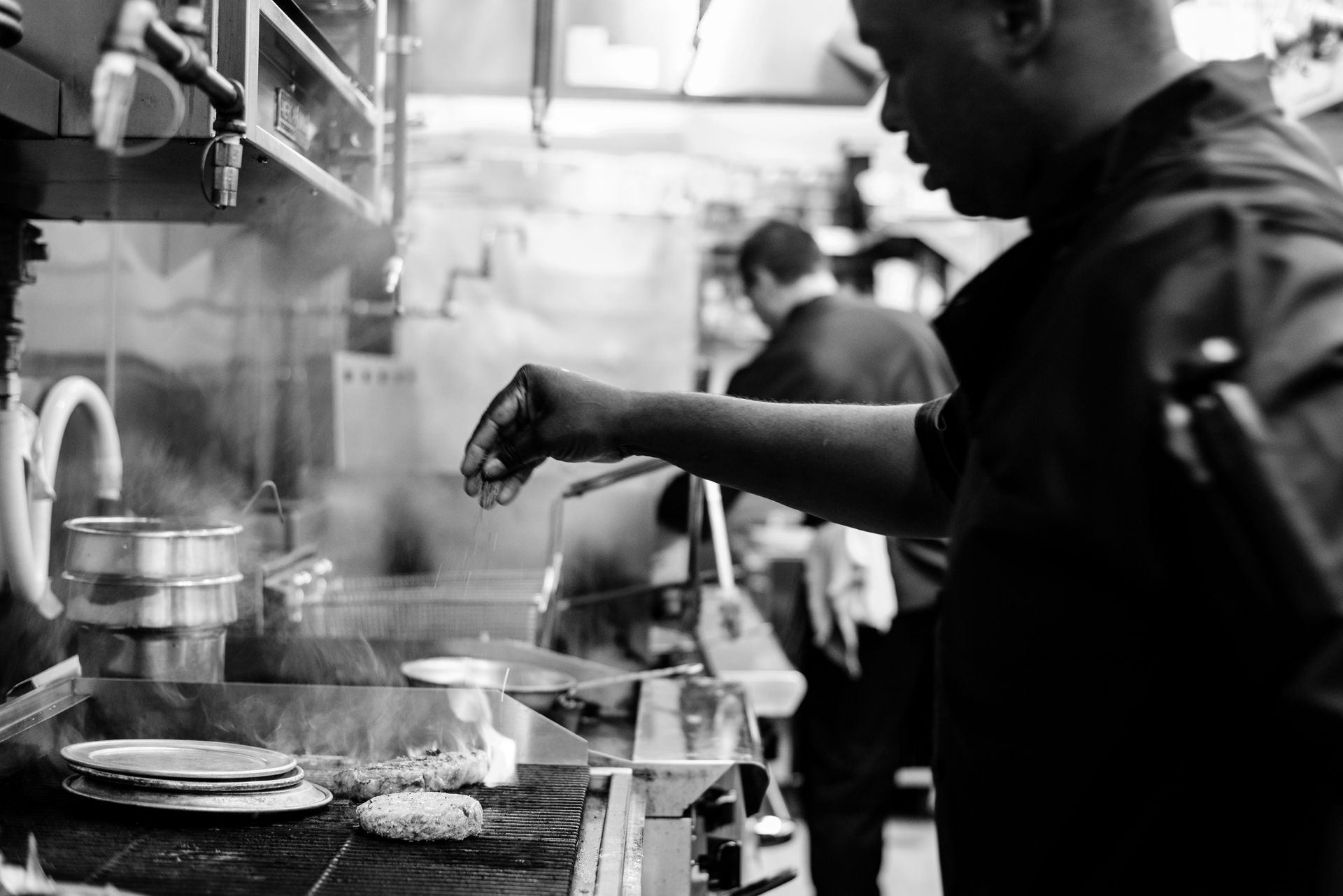 A man is cooking food in a kitchen in a black and white photo.