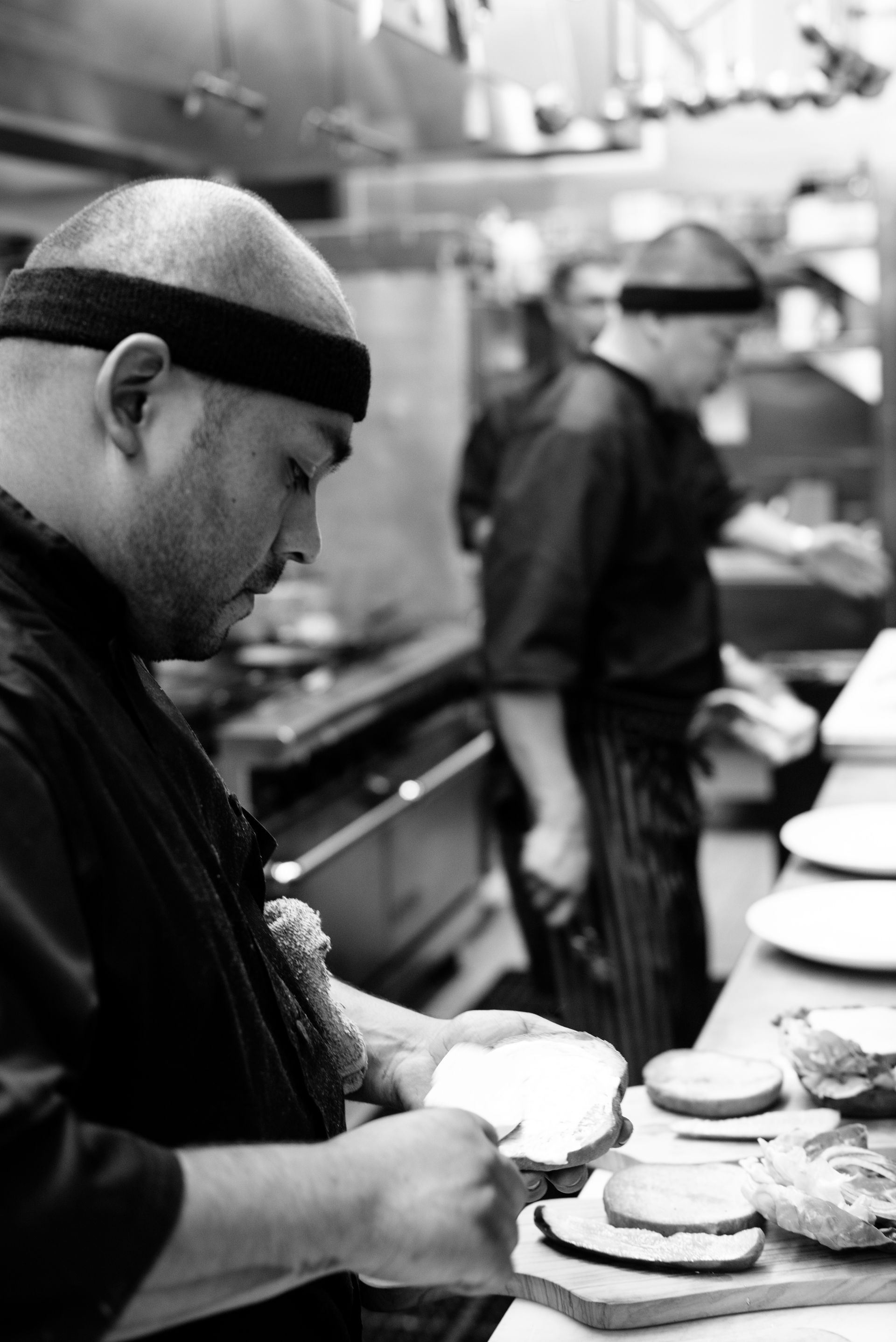 A black and white photo of a man preparing food in a kitchen