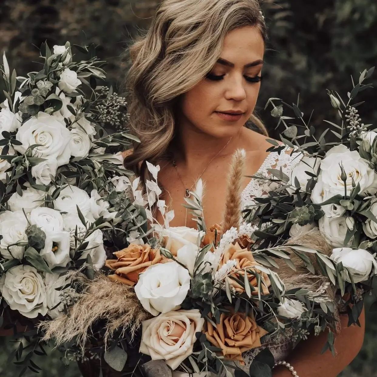 Woman with blonde hair, holding a bouquet of white, tan, and rust colored flowers.