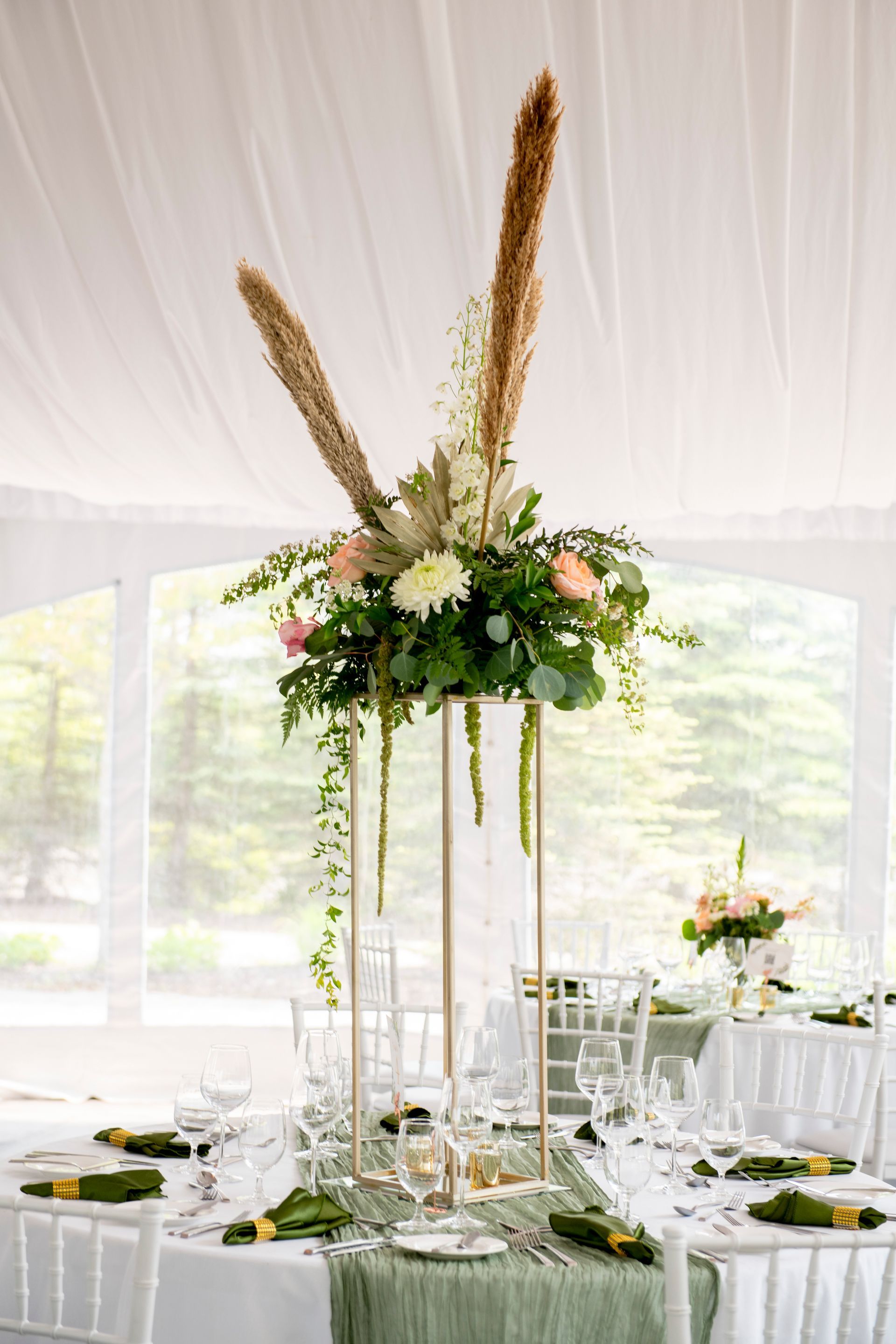Elegant wedding table setting with tall floral centerpiece.