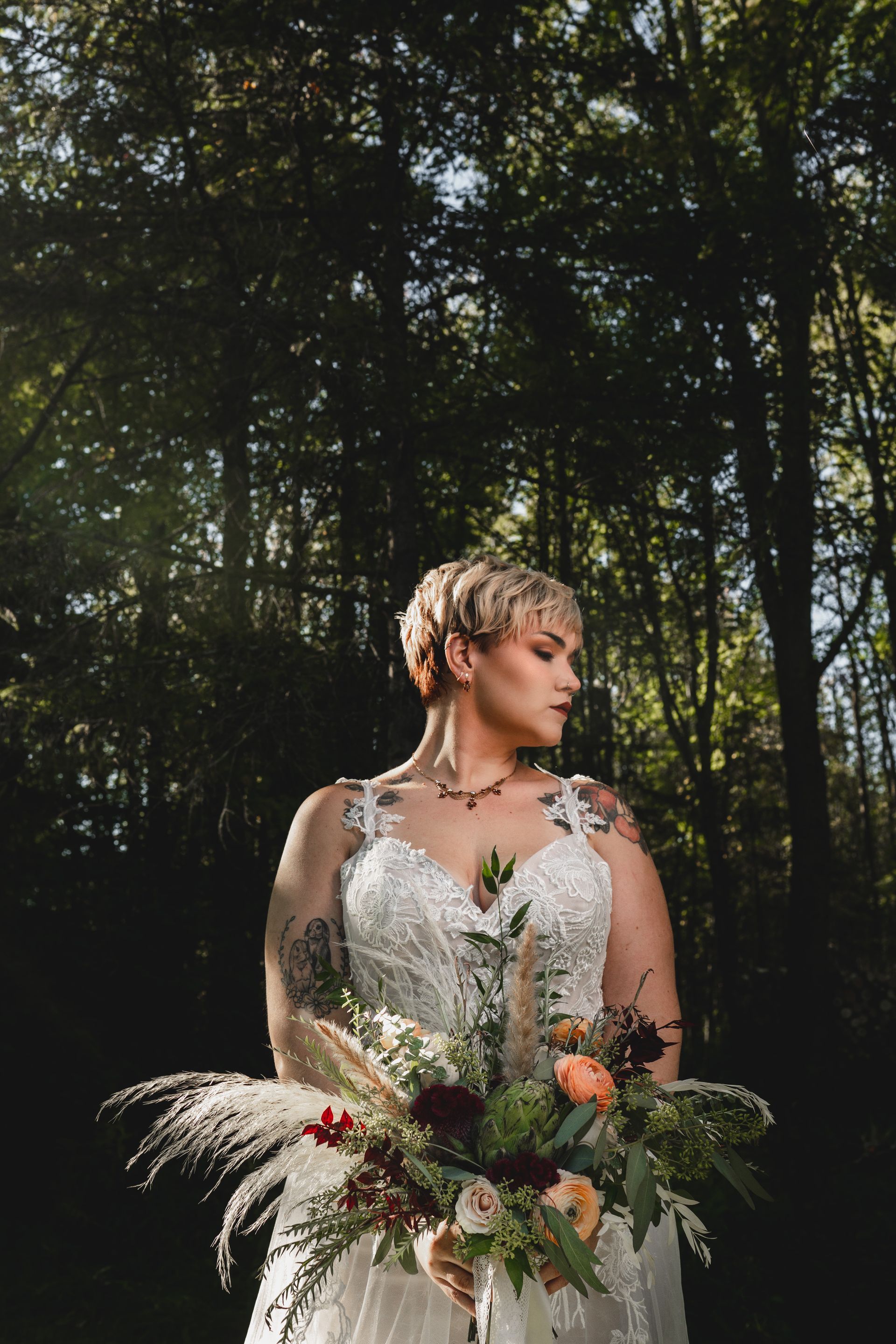 Bride in a white dress holds a bouquet, forest background.