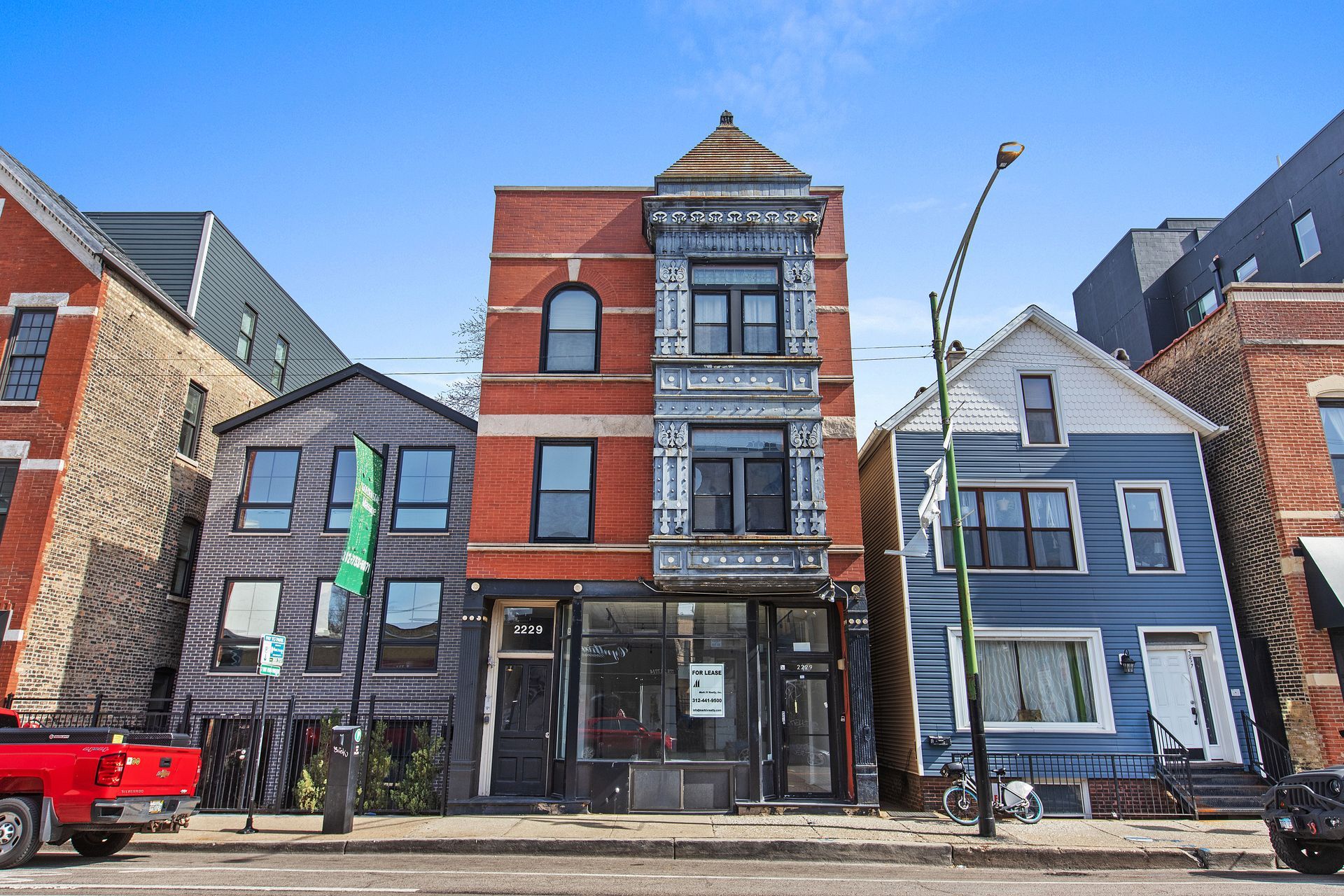 A red truck is parked in front of a building