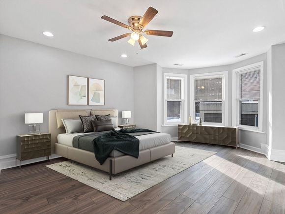 A bedroom with a bed , nightstands , a ceiling fan and two windows.