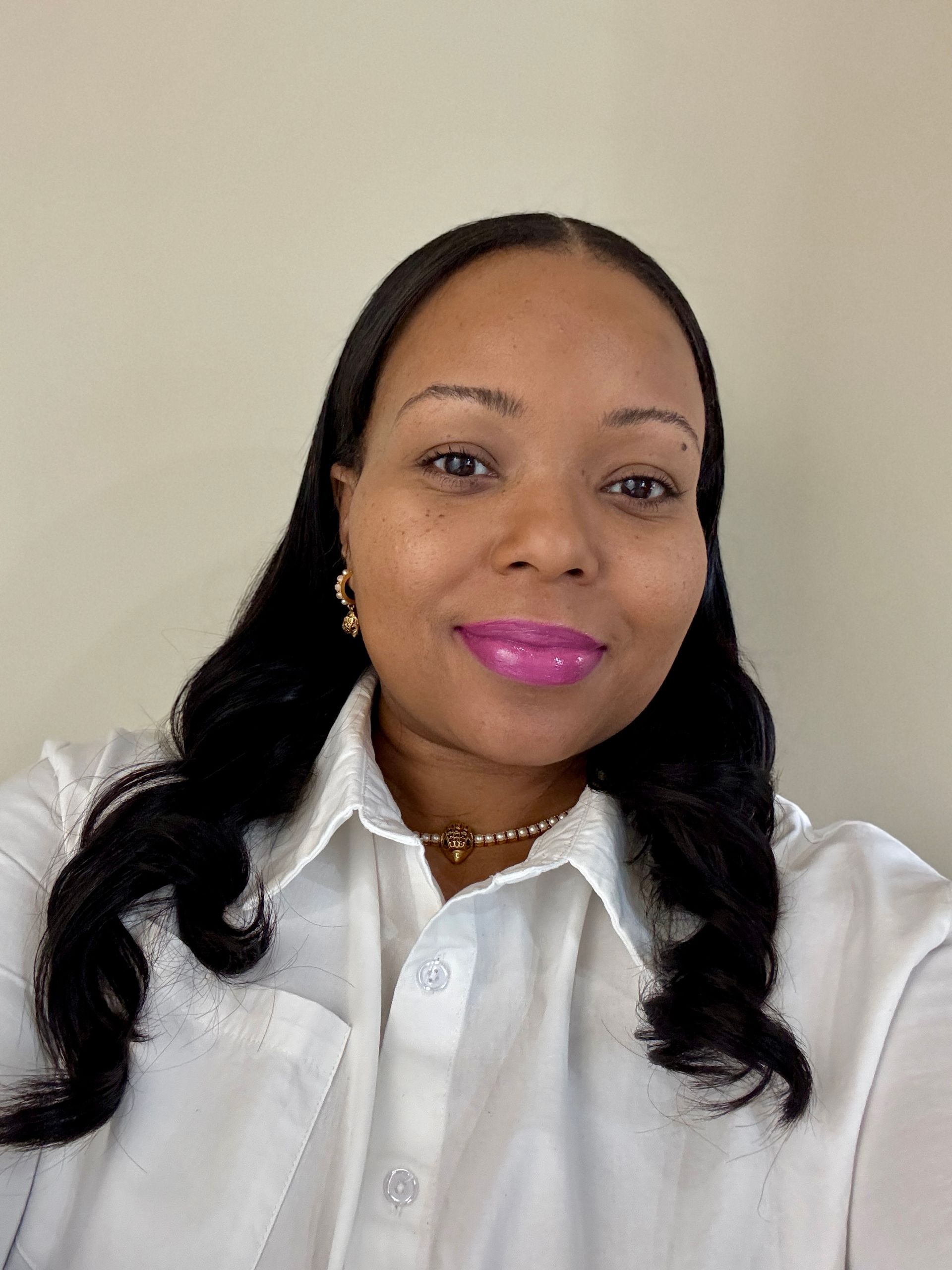 A woman wearing a white shirt and pink lipstick is taking a selfie.