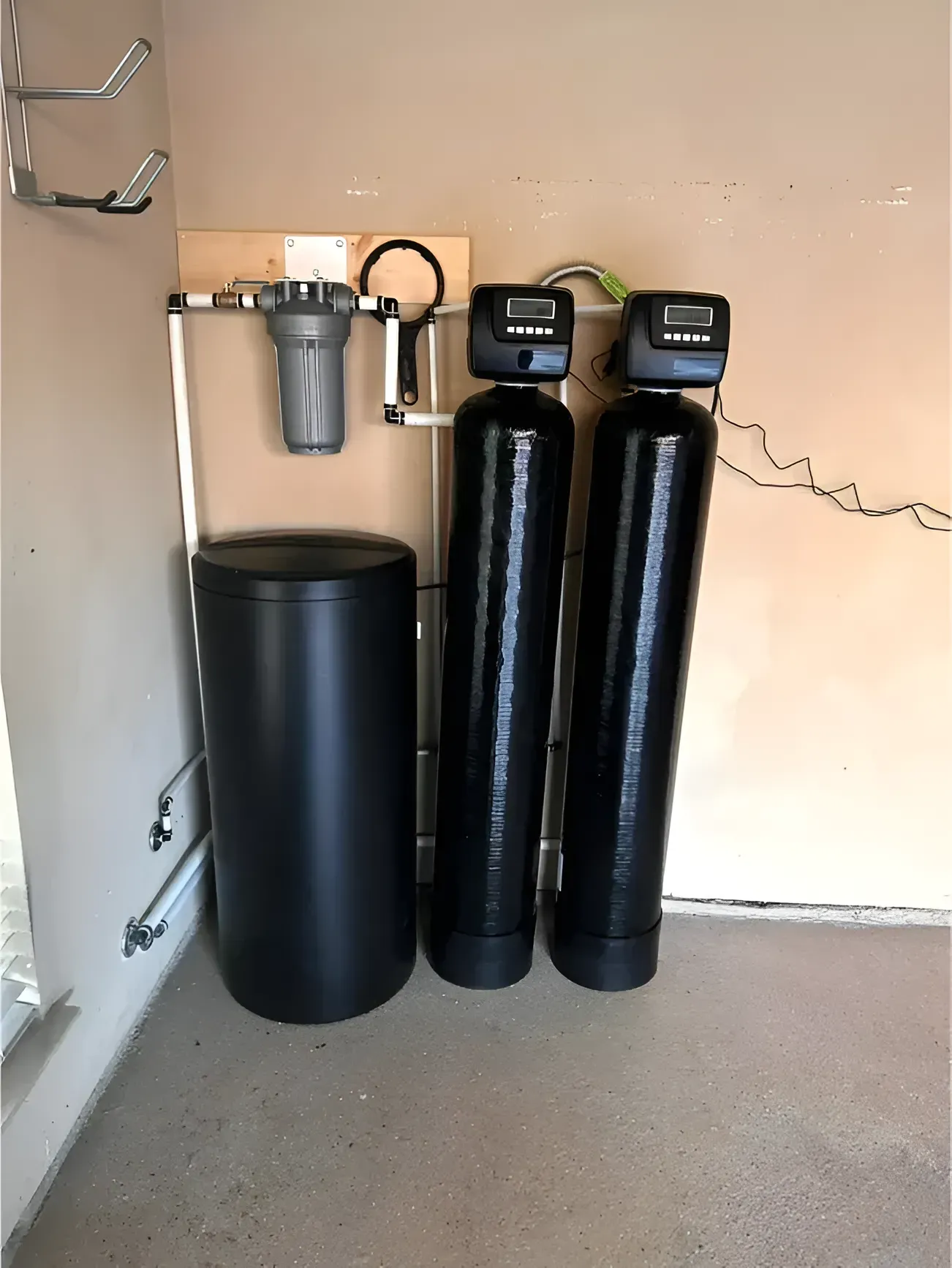 Water filtration and softening system in a garage setting: includes a pre-filter, two black tanks, and a salt tank.