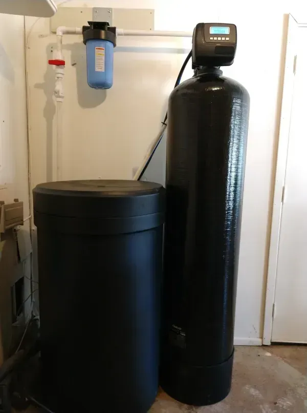Water softener system with a black tank, a brine tank, and a blue water filter.