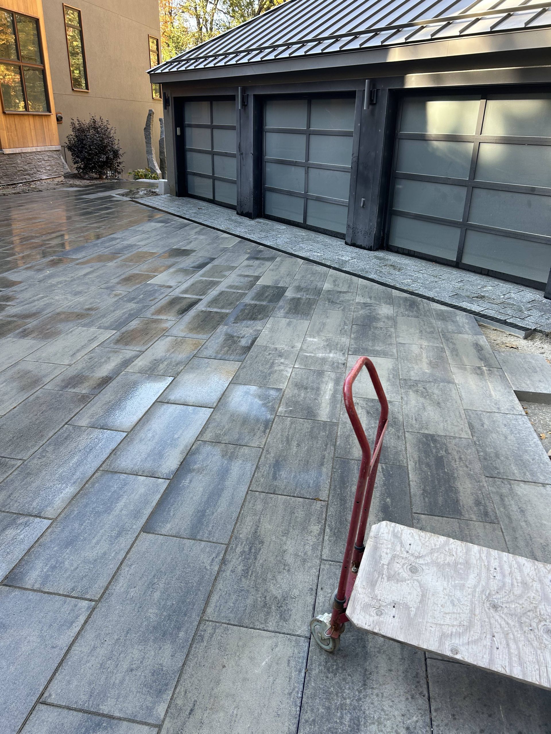 A wheelbarrow is parked in front of a garage door.