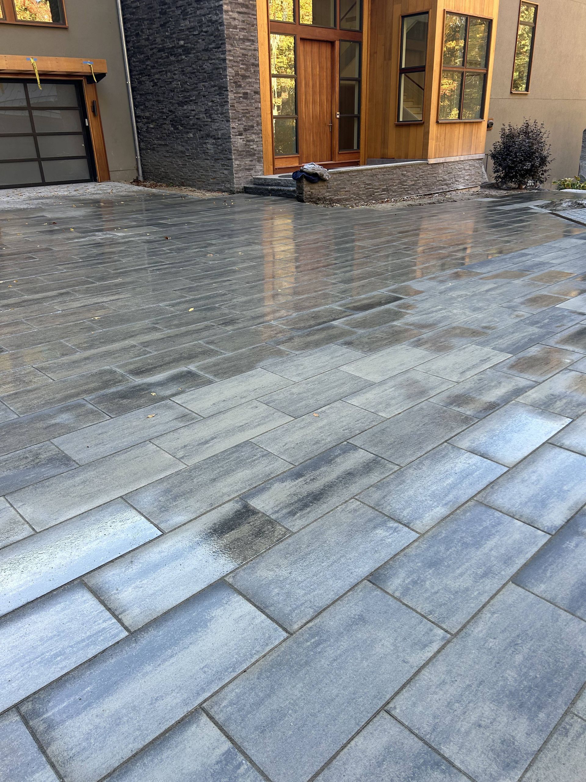 A brick driveway in front of a house with a garage door.