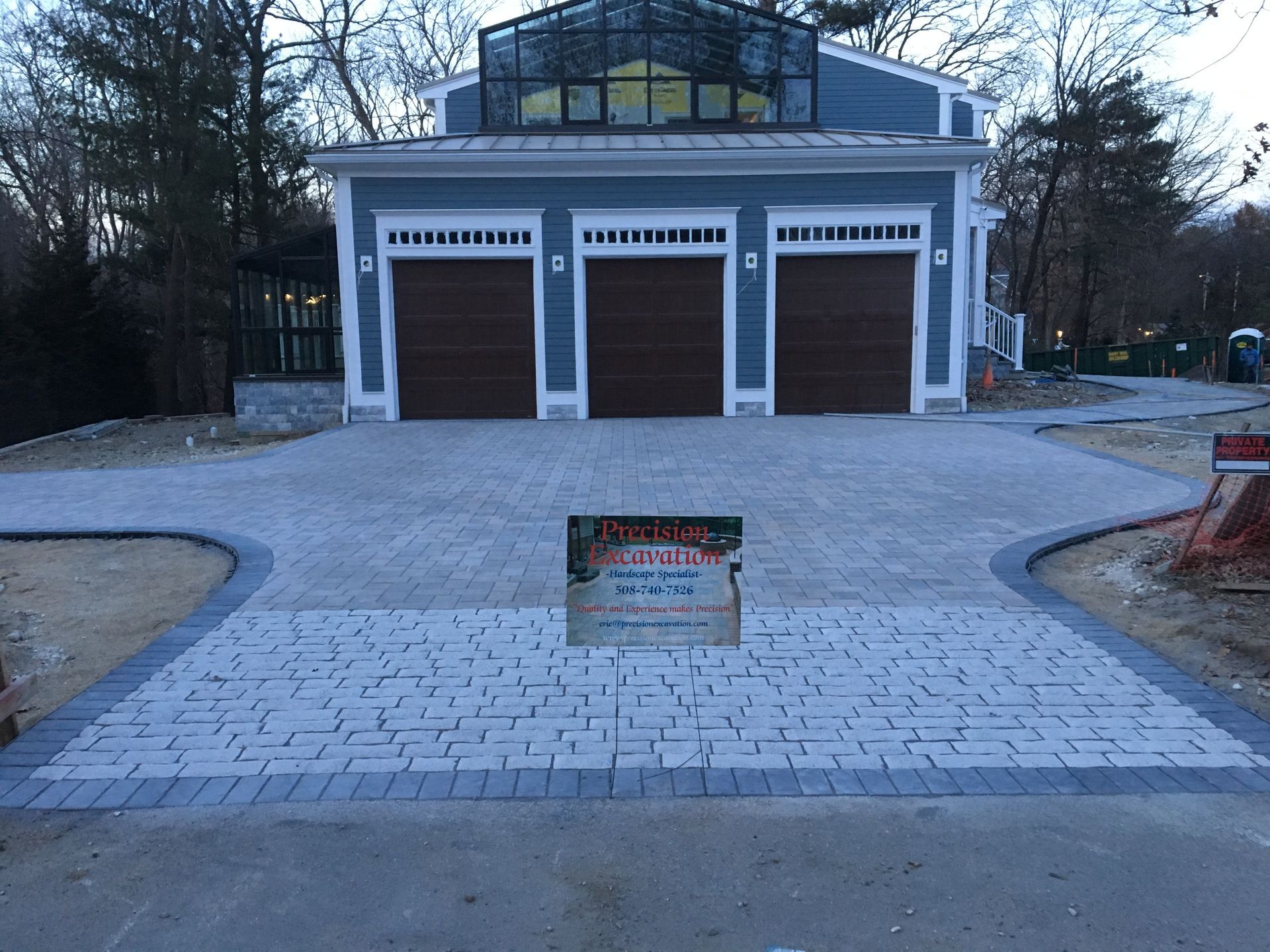 A driveway leading to a house with three garage doors