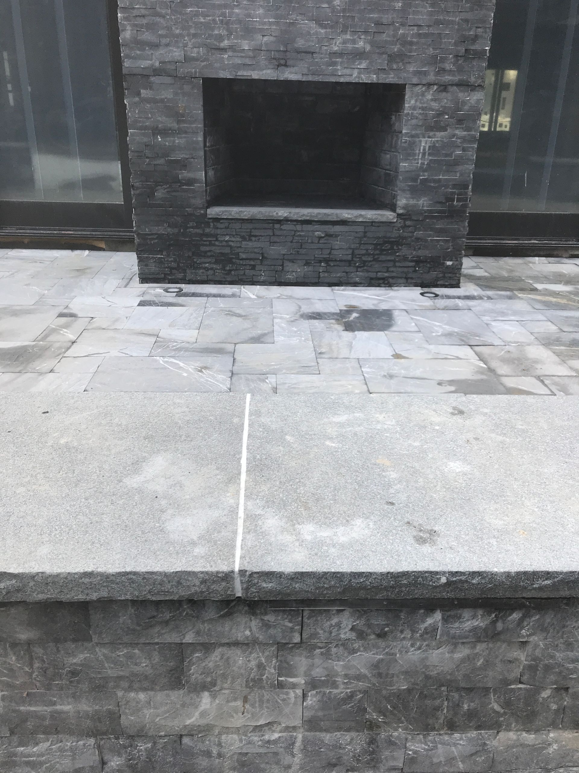 A brick fireplace is sitting on top of a stone patio.