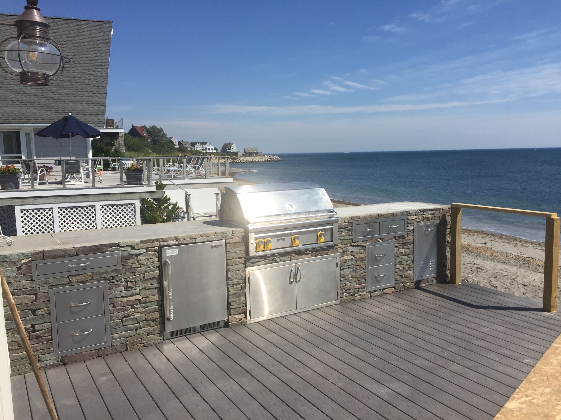 A deck with a grill and a view of the ocean