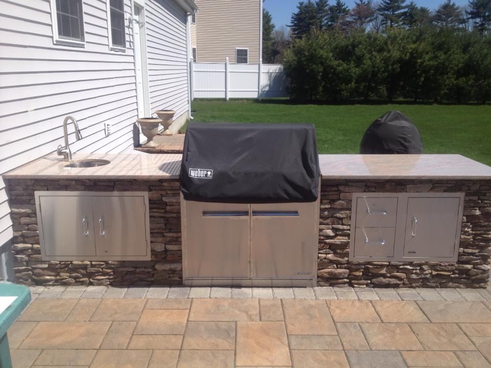 An outdoor kitchen with a grill and a sink