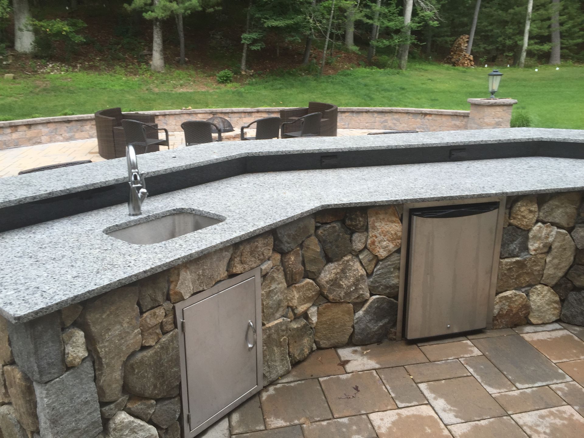 A stone counter top with a sink and a stainless steel dishwasher.